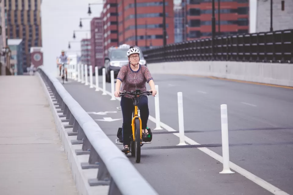 Woman on bicycle in protected bike lane on Boston bridge
